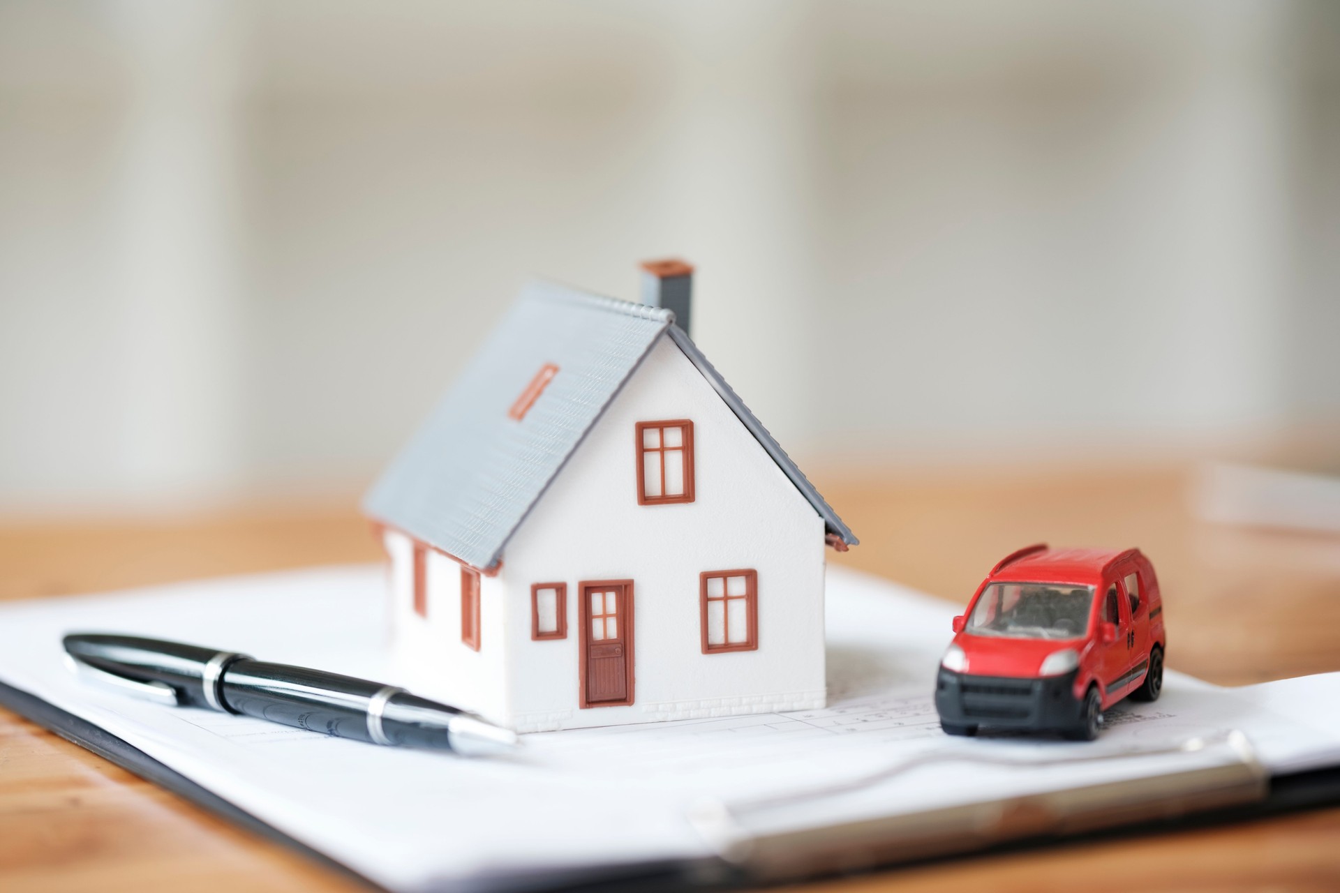 Haus- und Automodelle auf Vertrag, die Immobilien- und Fahrzeugvereinbarung symbolisieren